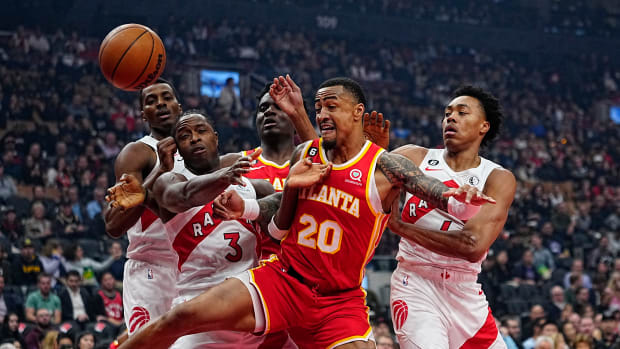 Hawks forward John Collins battles for the ball against Raptors defenders.